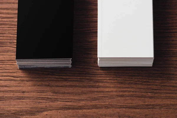 Stacks of white and black empty business cards on brown wooden surface — Stock Photo