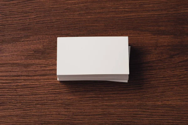 Vista superior de tarjetas de visita blancas apiladas en la superficie de madera marrón - foto de stock