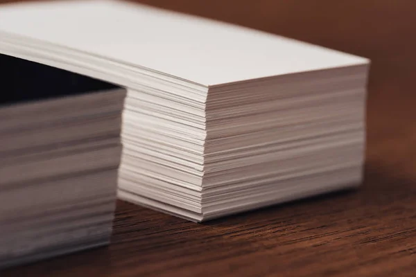 Mise au point sélective des cartes de visite vides blanches et noires empilées sur une surface en bois brun — Photo de stock