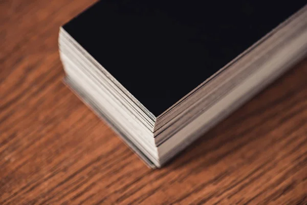 Pila de tarjetas de visita vacías negras en la mesa de madera marrón - foto de stock