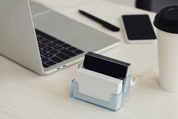 Card holder with black and white empty business cards, laptop and smartphone with blank screen on office table — Stock Photo