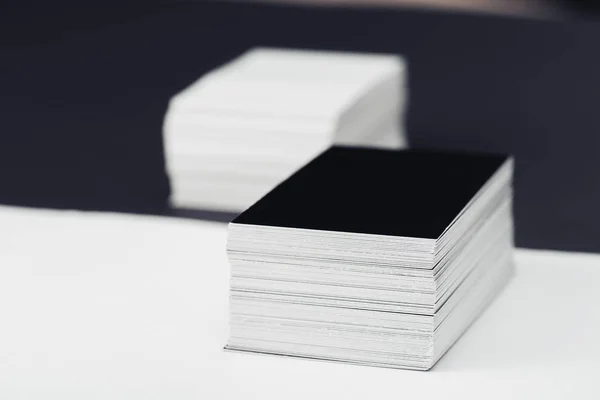 Enfoque selectivo de tarjetas de visita en blanco apiladas sobre fondo blanco y negro - foto de stock
