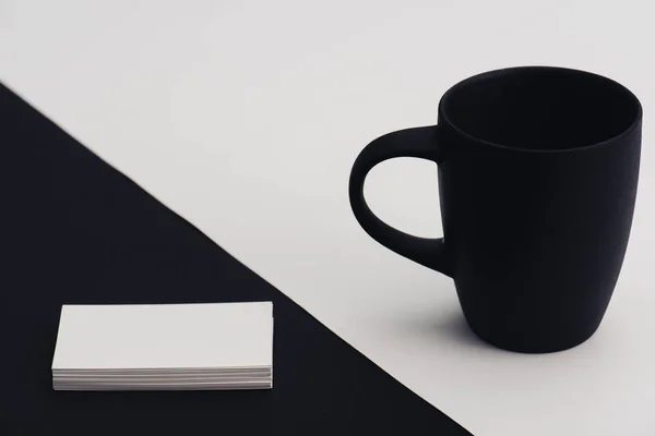 Schwarze Kaffeetasse und leere Visitenkarten auf schwarz-weißem Hintergrund — Stockfoto