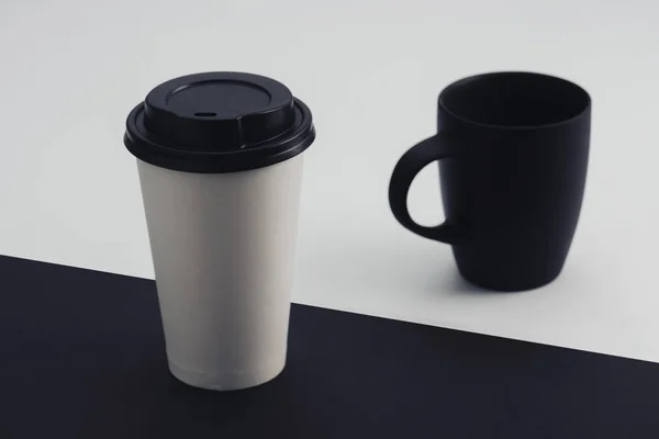 White paper cup and black coffee cup on black and white background — Stock Photo