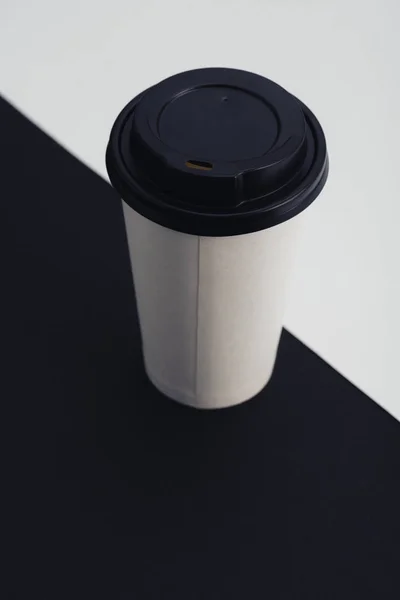 Белый бумажный стаканчик на черно-белом разделенном фоне — стоковое фото