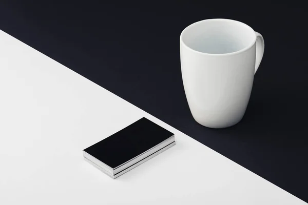 White coffee cup and black empty business cards on black and white background — Stock Photo