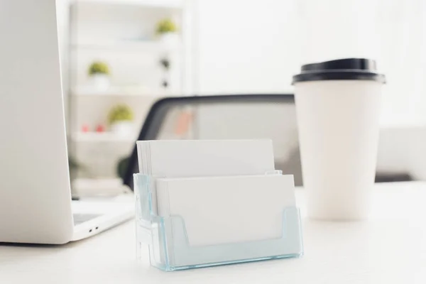 Card holder with empty business cards near paper cup and laptop on office desk — Stock Photo