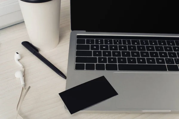 Tarjeta de visita vacía negro en el teclado portátil, pluma y auriculares en la mesa de la oficina — Stock Photo