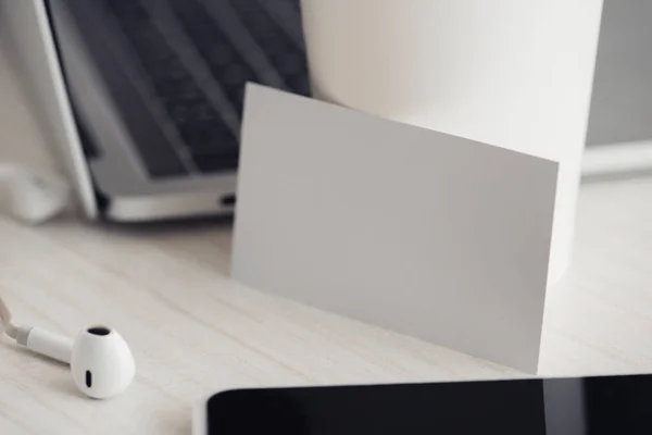 Empty white business card near laptop and smartphone on office desk — Stock Photo