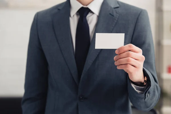 Cropped view of businessman in formal wear holding blank business card — Stock Photo
