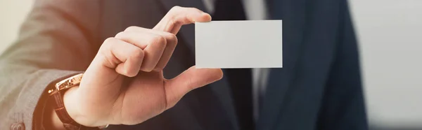 Partial view of businessman in formal wear showing empty business card at camera, panoramic shot — Stock Photo