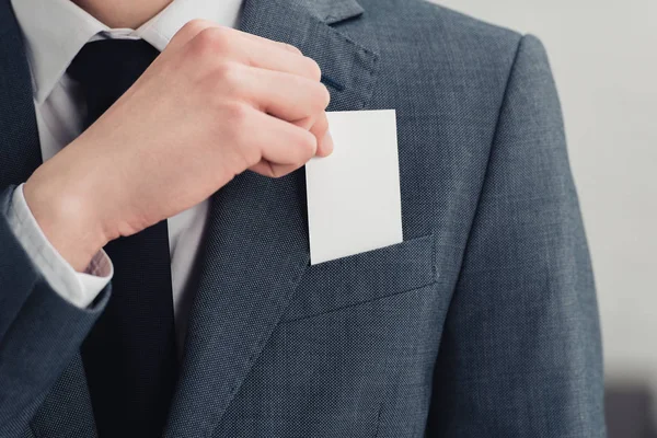 Vista recortada del hombre de negocios en traje con tarjeta de visita en blanco - foto de stock