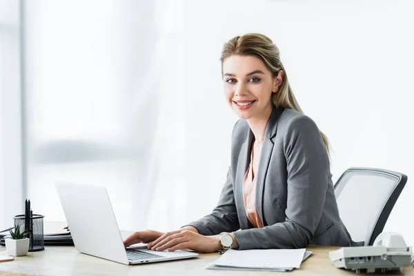 Donna d'affari felice seduta in ufficio e al lavoro sul computer portatile — Foto stock