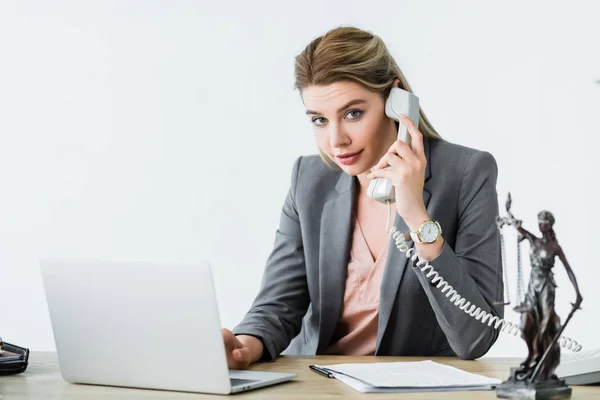 Beautiful lawyer sitting in office, looking at camera and talking on phone — Stock Photo