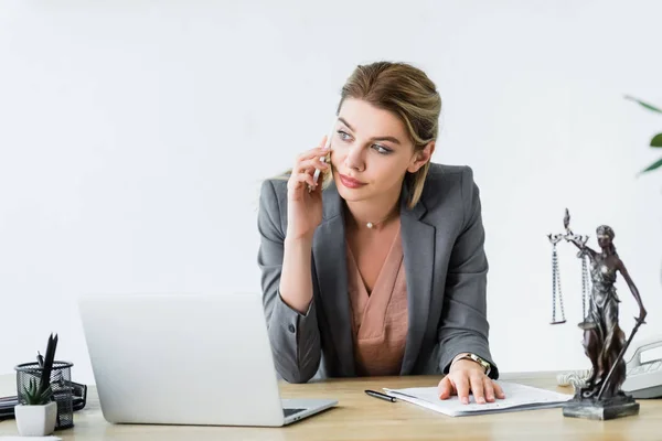 Serious lawyer sitting in office, looking away and talking on smartphone — Stock Photo
