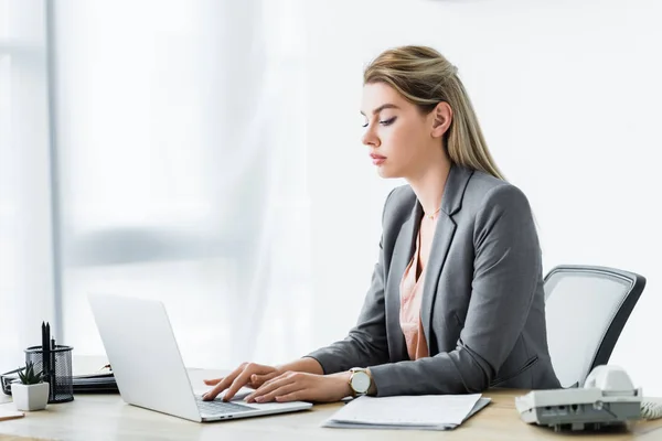 Mujer de negocios en ropa formal sentada en la oficina y trabajando en el ordenador portátil - foto de stock