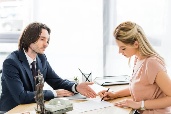 Бизнесмен, указывающий рукой на договор во время подписания адвокатом документа — стоковое фото