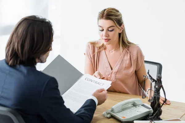 Selective focus of businessman holding contract in hands near woman — Stock Photo