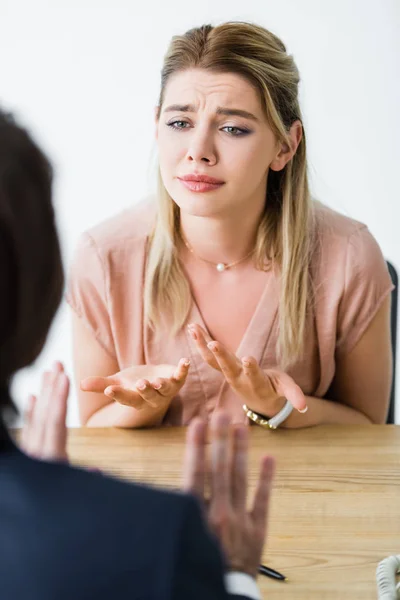Focalizzazione selettiva della donna sconvolta seduta in ufficio e che parla con un uomo d'affari — Foto stock