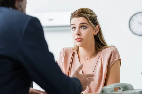 Hermosa mujer sentada en la oficina y hablando con el hombre de negocios - foto de stock