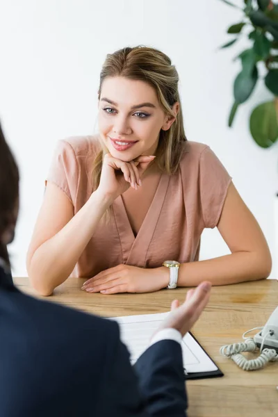 Charmante femme regardant homme d'affaires tout en étant assis au bureau — Photo de stock