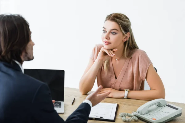 Enfoque selectivo de la mujer hermosa mirando al hombre de negocios y sentado en la oficina - foto de stock