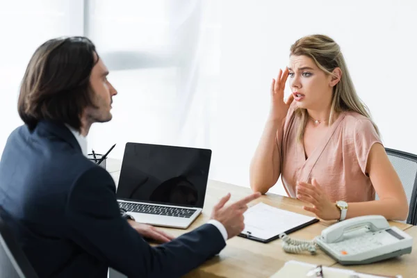 Upset woman sitting in office and talking with businessman — Stock Photo