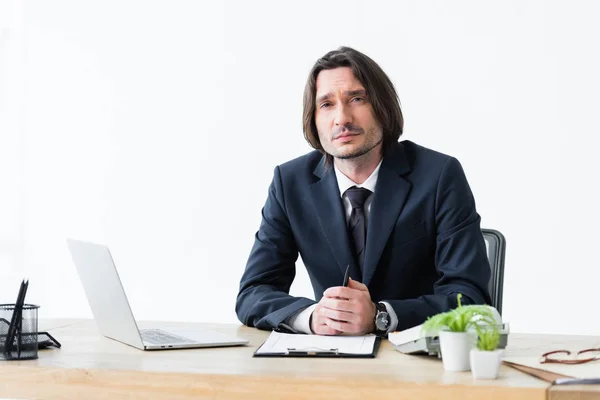 Seriöser Geschäftsmann sitzt im Büro und schaut in die Kamera — Stockfoto