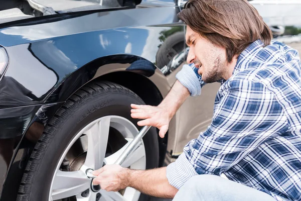 Müder Mann benutzt Werkzeug und wechselt kaputtes Rad am Auto, Kfz-Versicherungskonzept — Stockfoto