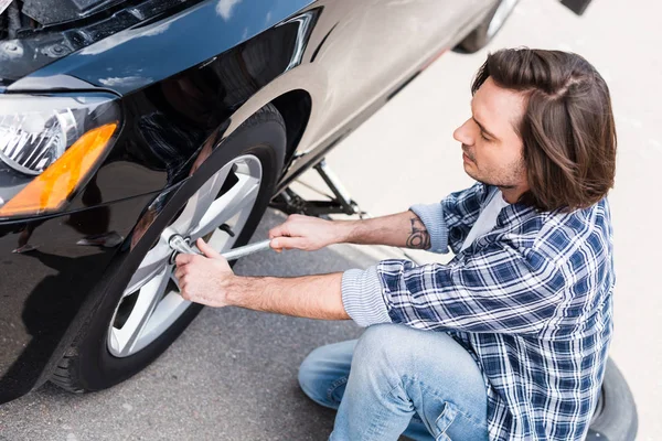 Man using tool, changing broken wheel on auto, car insurance concept — Stock Photo