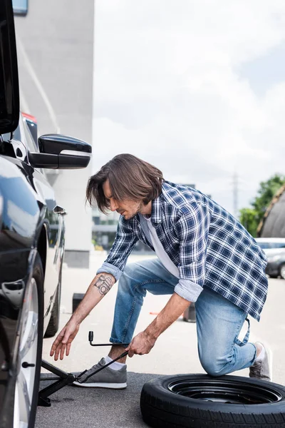 Man using jack tool and changing broken wheel on auto, car insurance concept — Stock Photo