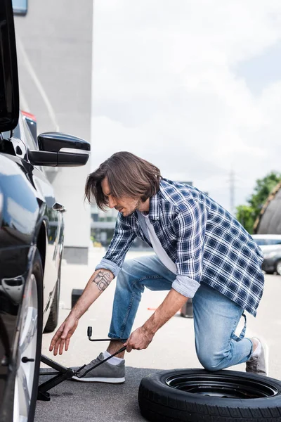 Homme utilisant Jack outil et changer la roue cassée sur l'automobile, concept d'assurance automobile — Photo de stock