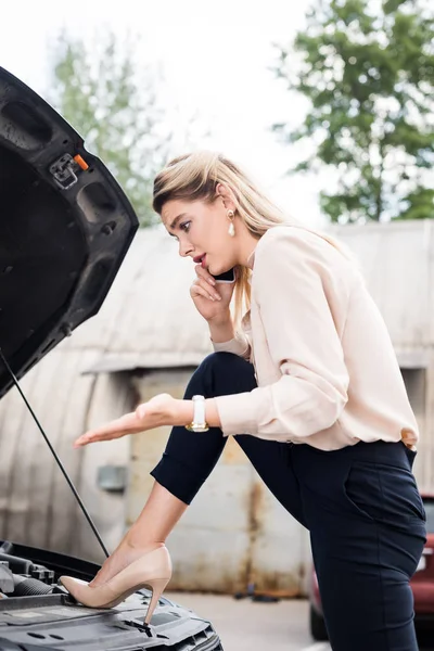 Donna d'affari parlando su smartphone e guardando rotto auto — Foto stock