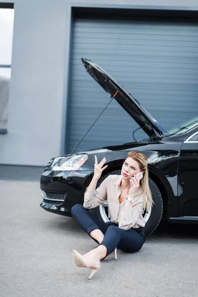 Деловая женщина разговаривает на смартфоне рядом со сломанным автомобилем, концепция страхования автомобиля — стоковое фото