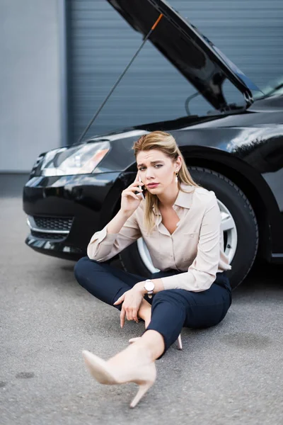 Upset businesswoman talking on smartphone near broken auto, car insurance concept — Stock Photo