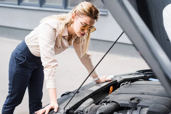 Businesswoman standing near broken auto and looking at open trunk, car insurance concept — Stock Photo