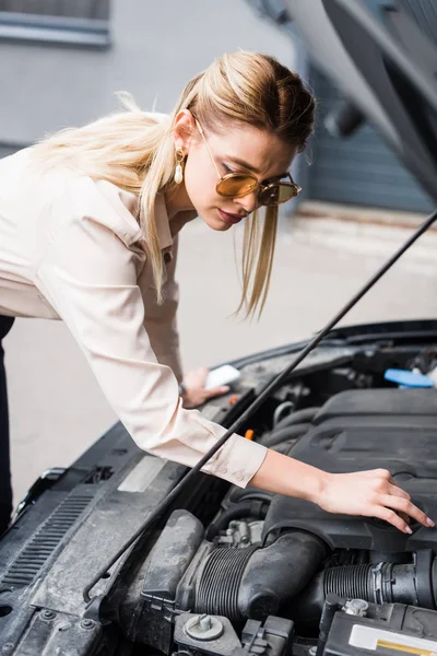 Beautiful businesswoman standing near broken auto and looking at open trunk, car insurance concept — Stock Photo