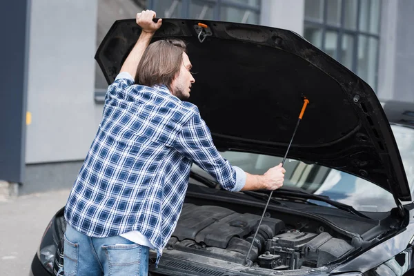 Man in casual clothes standing near broken auto with open trunk, car insurance concept — Stock Photo