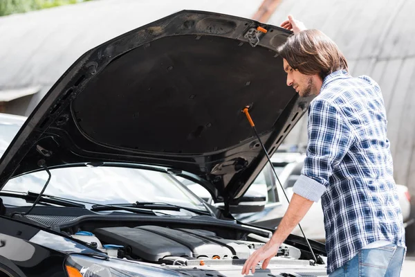 Hombre de pie cerca de coche roto con maletero abierto, concepto de seguro de coche - foto de stock