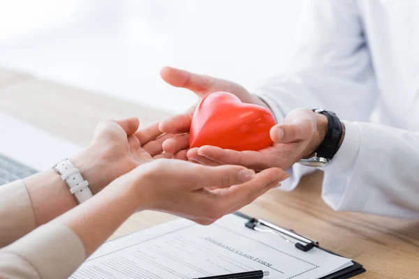 Visão cortada de médico e paciente segurando coração vermelho nas mãos, conceito de seguro médico — Fotografia de Stock