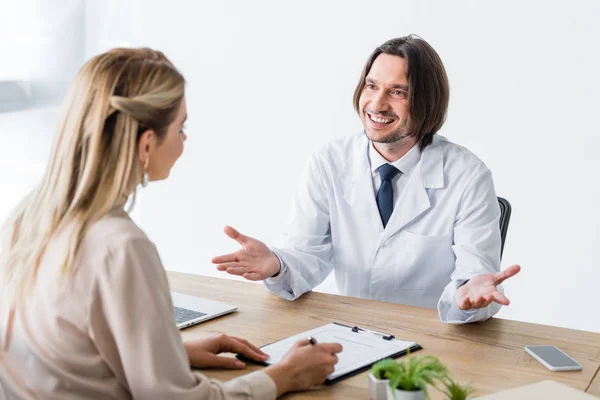 Patient assis avec un médecin heureux derrière une table en bois et document de signature — Photo de stock