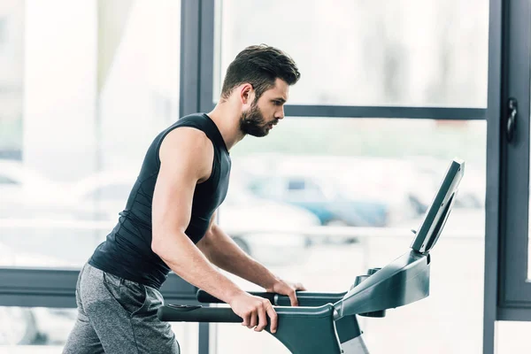 Handsome sportsman running on treadmill at sports center — Stock Photo