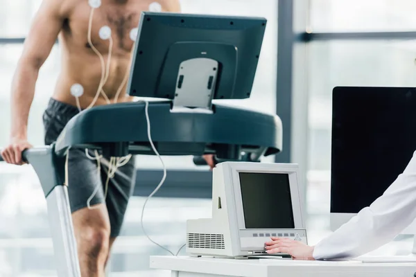 Vue recadrée du médecin effectuant un test d'endurance avec un sportif au gymnase — Photo de stock