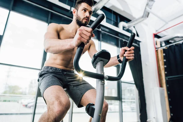 Guapo barbudo deportista entrenamiento en máquina elíptica en el gimnasio - foto de stock