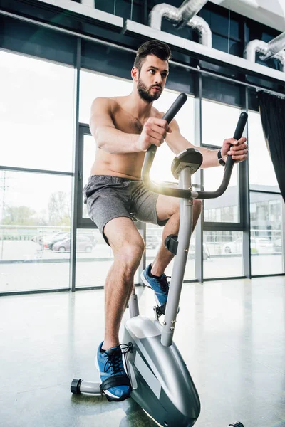 Handsome sportsman training on elliptical machine at sports center — Stock Photo
