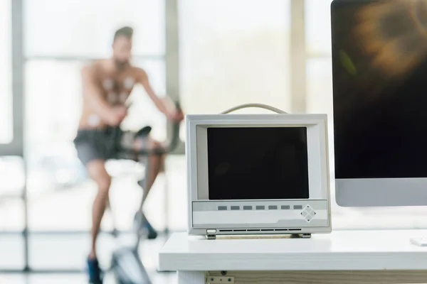 Selektive Fokussierung des Monitors mit leerem Bildschirm in der Nähe des Sportlertrainings an einem Crossgerät im Fitnessstudio — Stockfoto