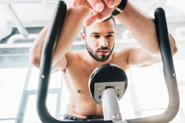 Apuesto deportista entrenamiento en elíptica máquina en gimnasio - foto de stock