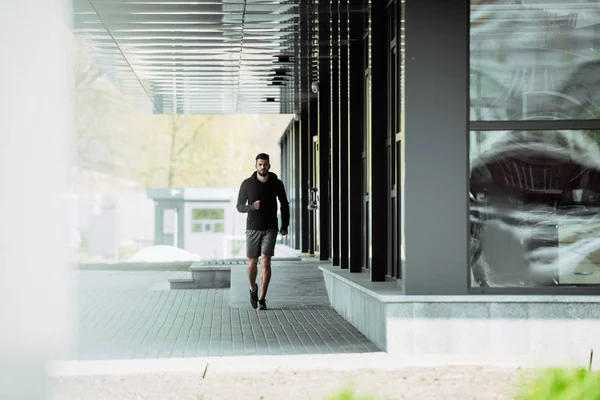 Handsome sportsman running near building — Stock Photo