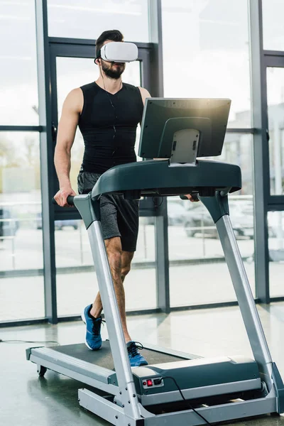 Sportsman in virtual reality headset running on treadmill at sports center — Stock Photo