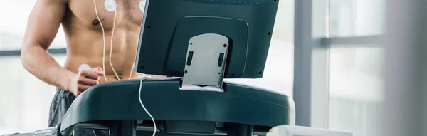 Prise de vue panoramique du sportif avec électrodes fonctionnant sur tapis roulant lors d'un test d'endurance en salle de gym — Photo de stock
